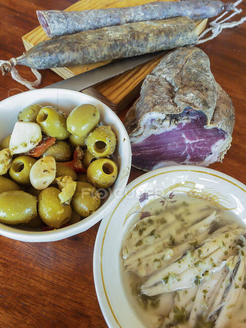 Traditional aperitif - Sausages, olives and anchovies — Stock Photo