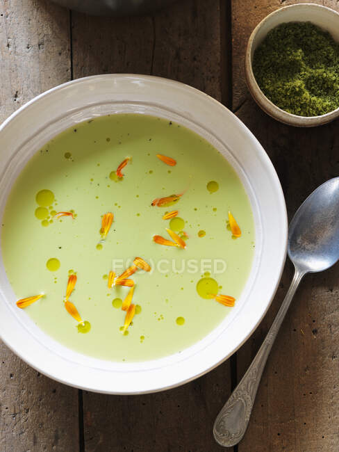 Cream of pea soup with flower petals — Stock Photo