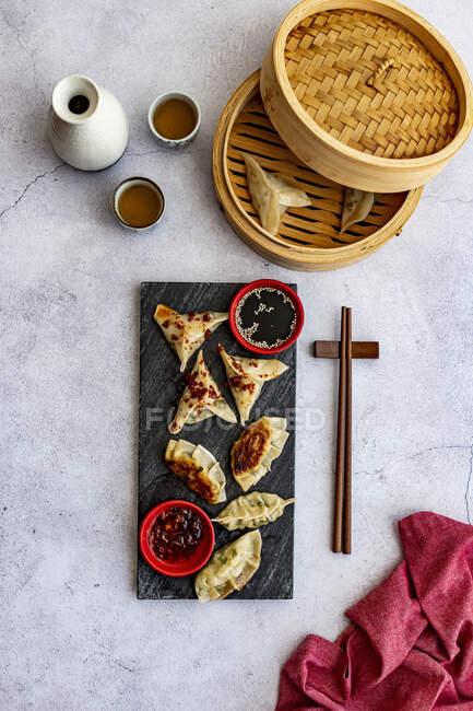 Steamed prawn dumplings and chicken pot stickers with chili oil — Stock Photo