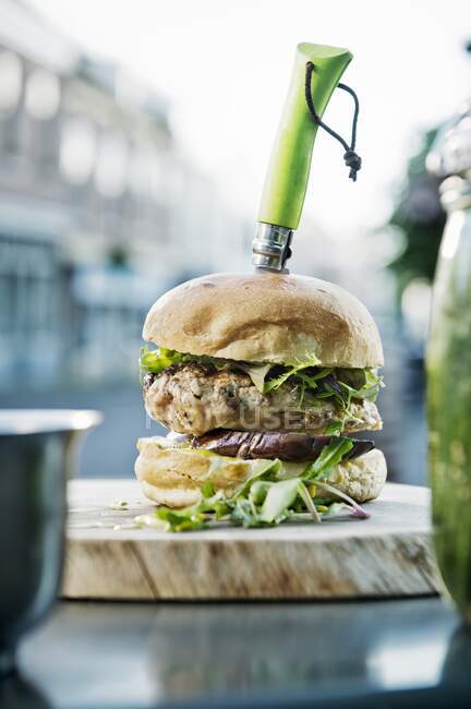 Close-up shot of delicious burger with a knife in a bistro — Stock Photo