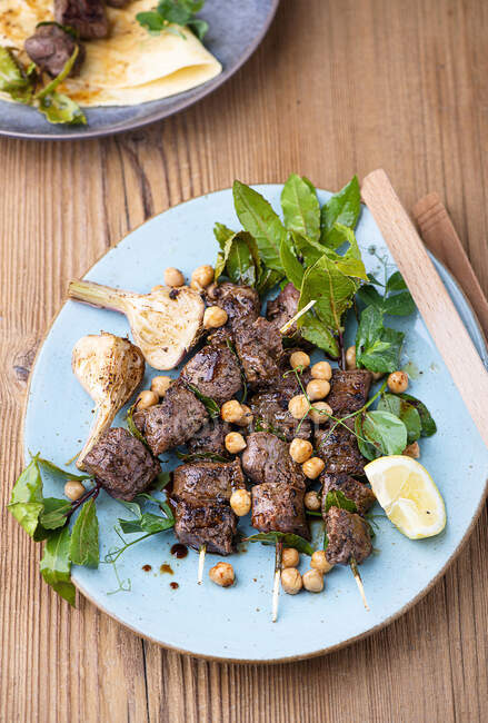 Lamb skewers with chickpeas salad and grilled garlic — Stock Photo