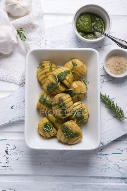 Hasselback-Kartoffeln mit Rosmarin, grünem Pesto und gewürzten Hefeflocken — Stockfoto