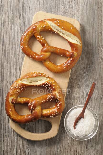 Dos pretzels en una tabla de madera - foto de stock