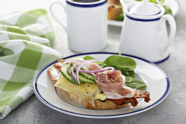 Breakfast sandwich with prosciutto, avocado, eggs and bacon — Stock Photo