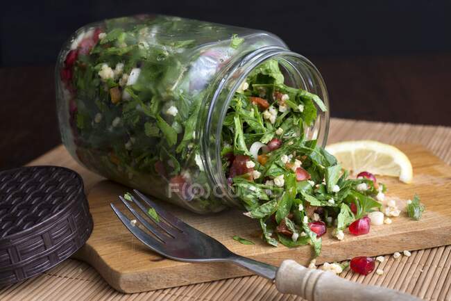 Millet taboule in a glass jar with pomegranate seeds, parsley and mint — Stock Photo