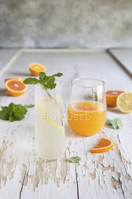 Orange and Lemon Gin Cocktails in glasses with ingredients on rustic wooden surface — Stock Photo