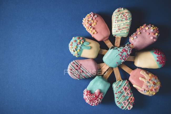 Different cake pops in the shape of ice lollies with brightly coloured icing — Stock Photo