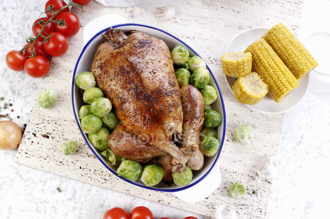 Roast chicken with brussels sprouts and corn cobs — Stock Photo
