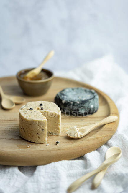Veganer fermentierter Käse auf Holztablett mit Marmelade und Löffeln — Stockfoto