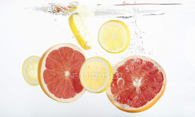 Citrus slices falling into fresh water — Stock Photo