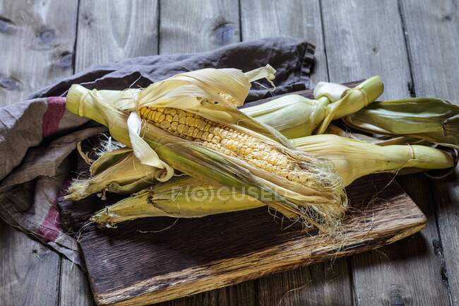 Une épi de maïs sur une planche de bois — Photo de stock