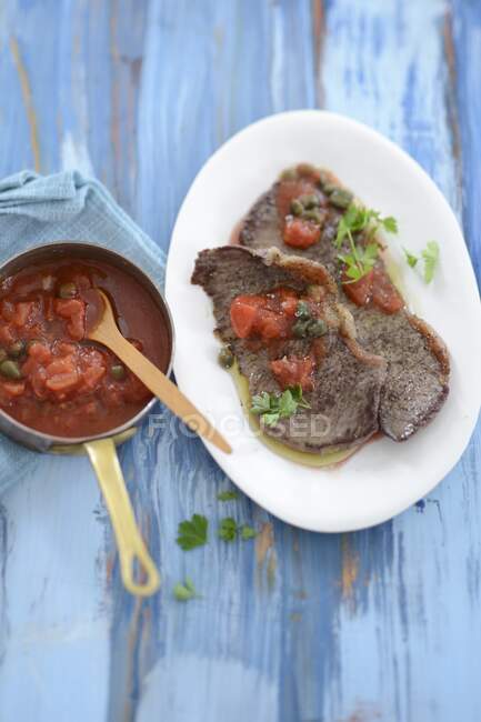 Beef slices with tomato and caper sauce — Stock Photo