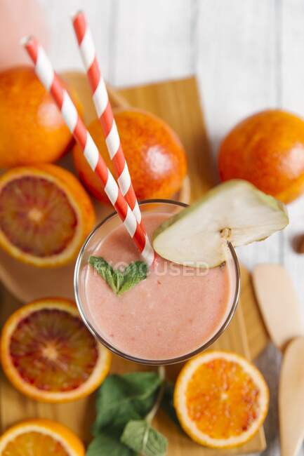 Un frullato di arancia rossa con una cannuccia in un bicchiere — Foto stock