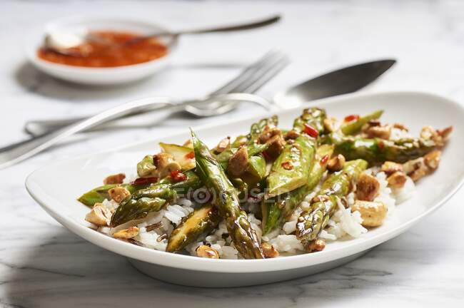 Fried green asparagus in sweet and spicy sauce with cashews on basmati and wild rice — Stock Photo