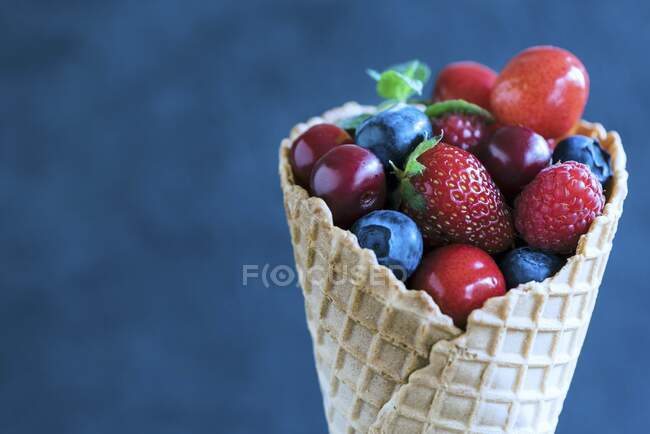 Baies et cerises fraîches dans un cône de crème glacée — Photo de stock