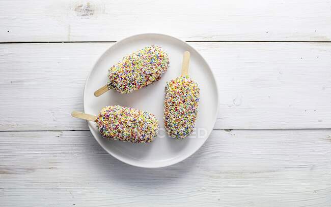 Three ice lollies with sticks, covered in hundreds and thousands — Stock Photo