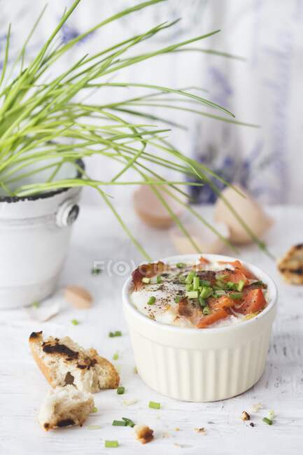 Печёное яйцо с беконом, помидорами и луком в мини-миске — стоковое фото