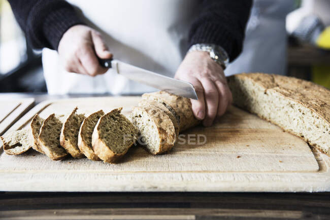 Freshly baked bread being sliced — Stock Photo