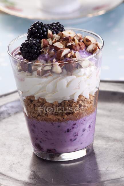 Cream and blackberries dessert with hazelnuts in glass — Stock Photo