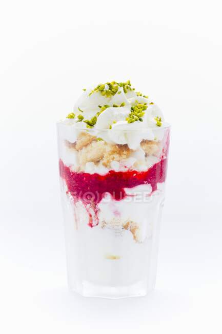 Yogur helado con pastel de vainilla, merengues, puré de frambuesas, pistachos y crema - foto de stock