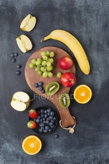 Various fruits on a wooden board with a grey background (top view) — Stock Photo