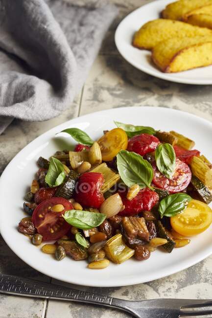 Caponata with peppers and cherry tomatoes served with polenta slices — Stock Photo