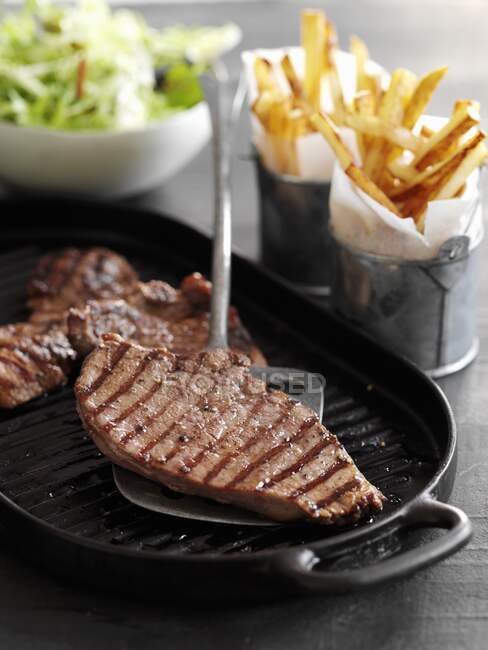 Steaks minute avec frites et salade — Photo de stock