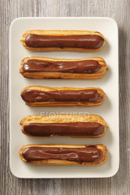 Chocolate eclairs on a serving plate (seen from above) — Stock Photo