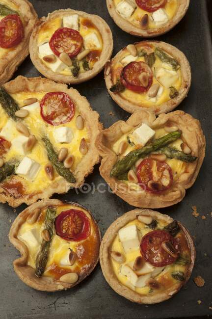 Asparagus, tomato, feta and pine nut tarts (seen from above) — стокове фото