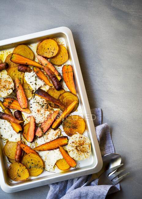 Roast vegetables with goat's cheese, garlic and herbs on an oven tray — Stock Photo