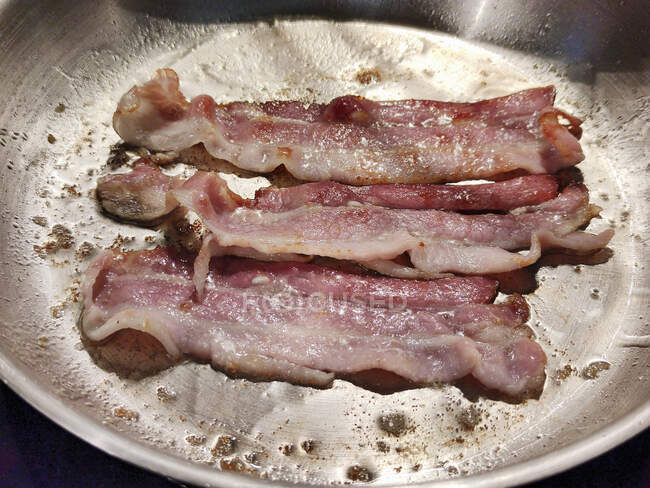 Bacon being fried in a pan — Stock Photo