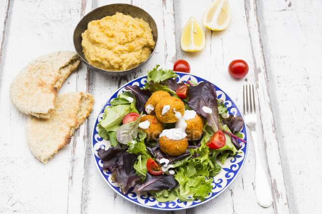 Falafel with yoghurt dip on lettuce with hummus and flat bread — Stock Photo