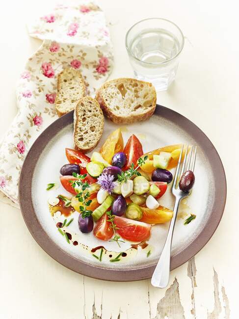 Lacto fermented tomatoes, cucumbers, and olives served with herbs and garlic bread — Stock Photo