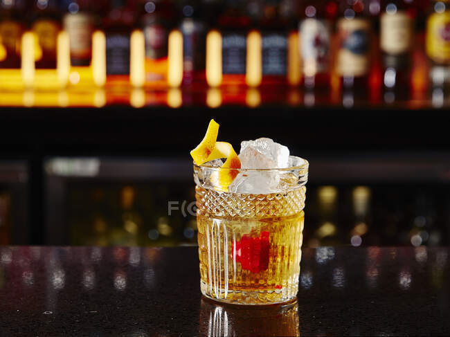 OldFashioned cocktail con ciliegia e scorza di limone sul bancone del bar — Foto stock