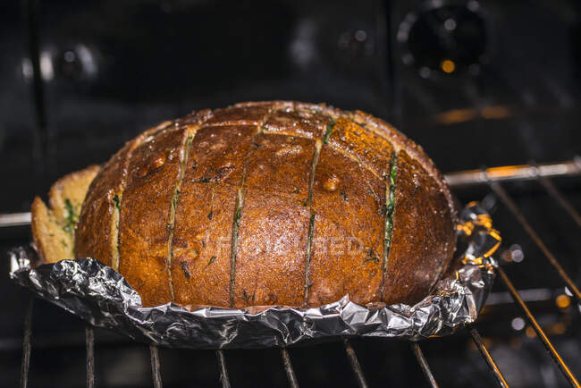 Pan de fiesta de ajo y hierbas en el horno - foto de stock