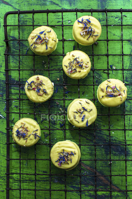 Kekse mit Glasur und essbaren Blüten auf einem Kühlregal — Stockfoto