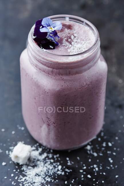 Blueberry smoothie with coconut and edible flowers — Stock Photo