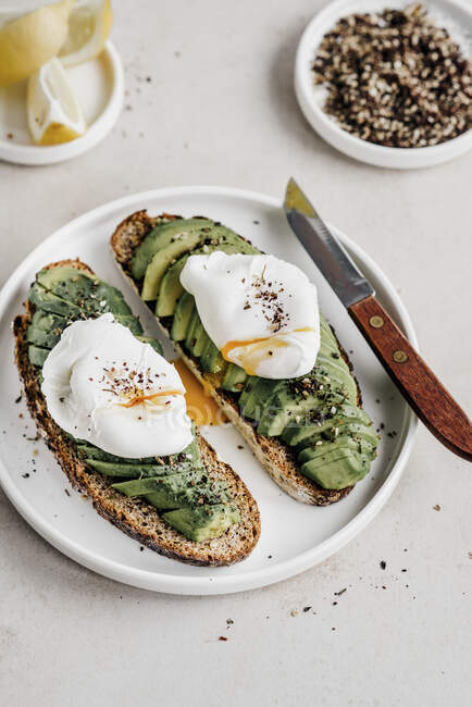 Avocado toasts with poached eggs served on plate — Stock Photo