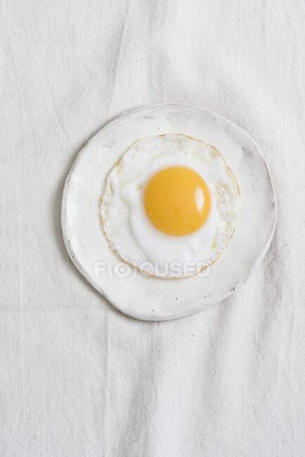 Fried egg on a white plate — Stock Photo