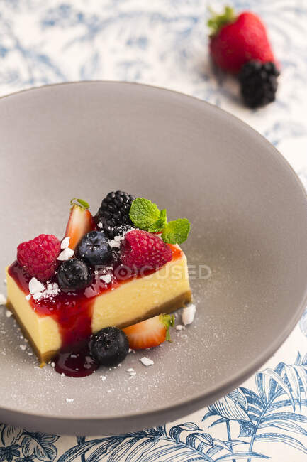 Ein Stück Käsekuchen mit Fruchtsauce und frischen Beeren — Stockfoto