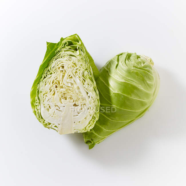 Pointed cabbages, whole and halved, on a white surface — Stock Photo