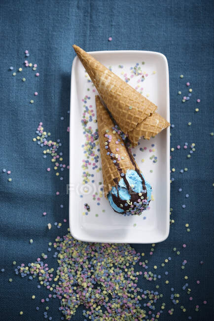 Blue vegan ice cream with chocolate sauce and sugar confetti in cones — Stock Photo
