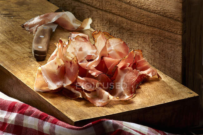 Sliced ham on a wooden board with a knife — Stock Photo