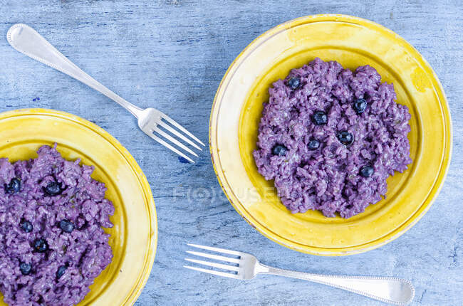 Arándanos con arroz dulce de color púrpura en platos - foto de stock