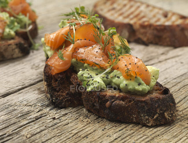 Pane alla griglia con avocado, salmone affumicato ed erbe aromatiche — Foto stock