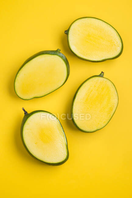 Moitiés de mangue sur fond jaune (vue du dessus) — Photo de stock