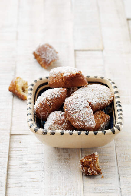 A bowl of homemade, deep-fried pastries with icing sugar — Stock Photo