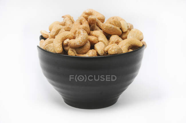 Roasted and salted cashews in a black bowl — Stock Photo