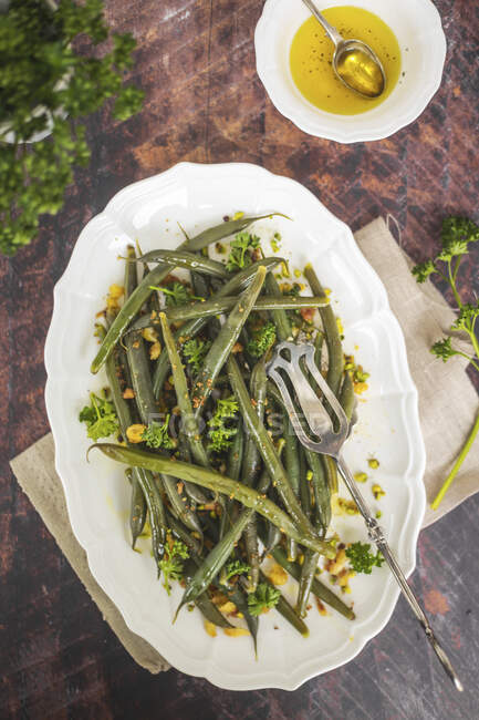 Green beans with bread crumbs oil curly parsley and pistachios — Stock Photo