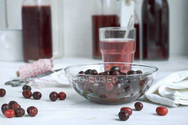 Cherries in glass bowl and on white table surface — Stock Photo